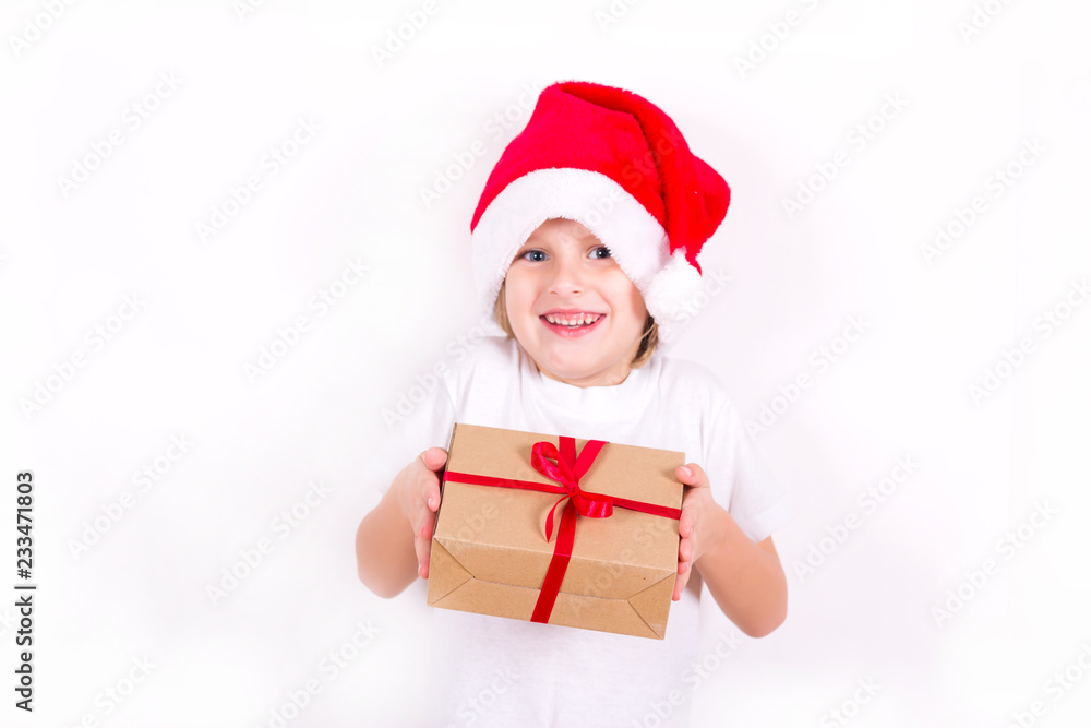 Happy boy in Santa red hat holding Christmas gift in hand. Christmas concept. Happy boy in Santa red hat holding Christmas gift in hand. Christmas concept.