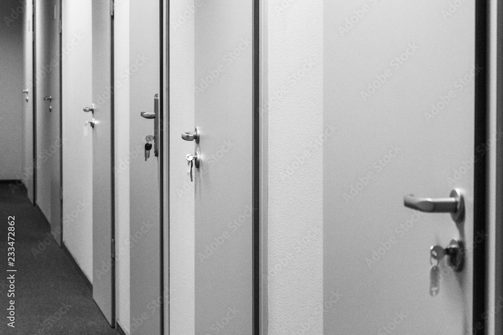 Long corridor in an office building. Many closed doors. Doors with keys in locks. Office theme. Work schedule. Workplace office workers. Long corridor in an office building. Many closed doors. Doors with keys in locks. Office theme. Work schedule. Workplace office workers.