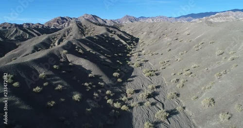 Aerial drone scene of desertic colorfull hills and mountains made of sand and rock. Flying from dry river to panoramic view of landscape. San Juan, Calingasta, argentina photo