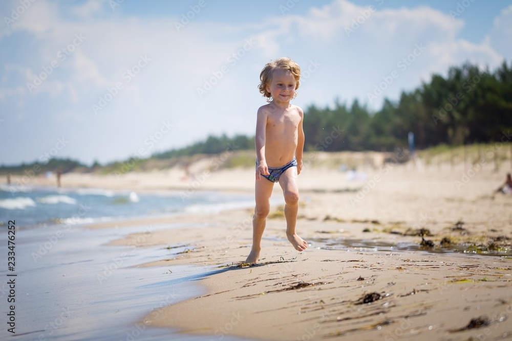 Young caucasian boy playing on sea shore at sunny summer Young caucasian boy playing on sea shore at sunny summer