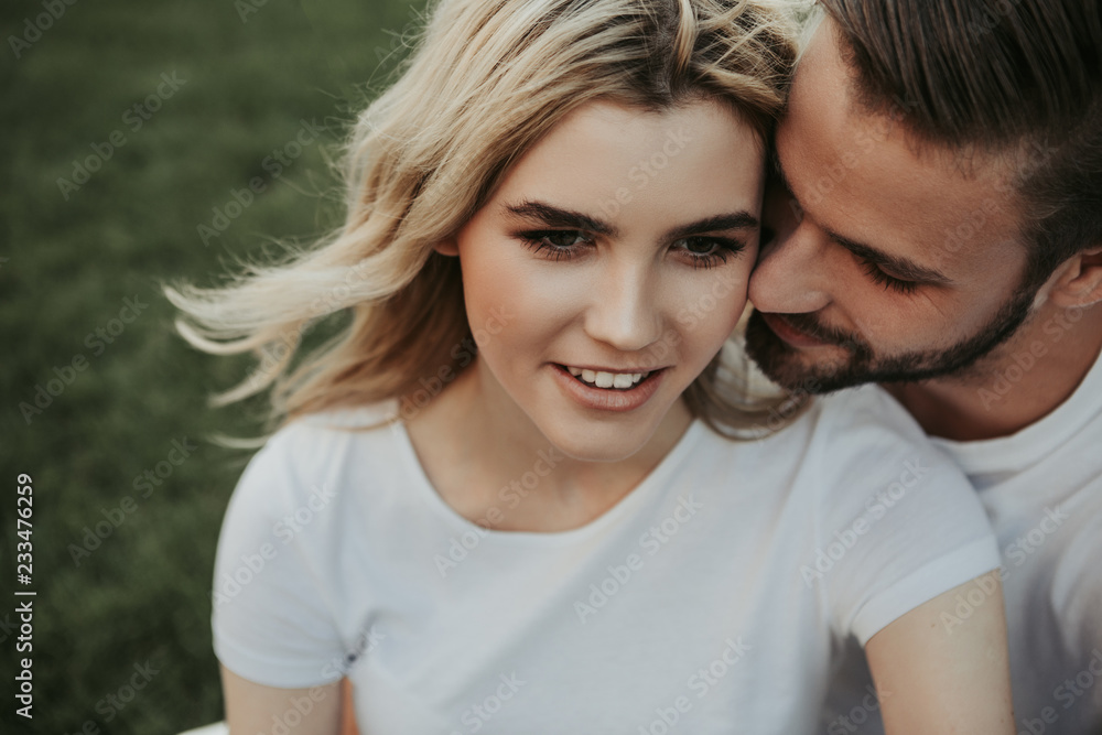 Blithesome handsome man is inclining to girlfriend and touching to her cheek. She looking ahead with light smile Blithesome handsome man is inclining to girlfriend and touching to her cheek. She looking ahead with light smile