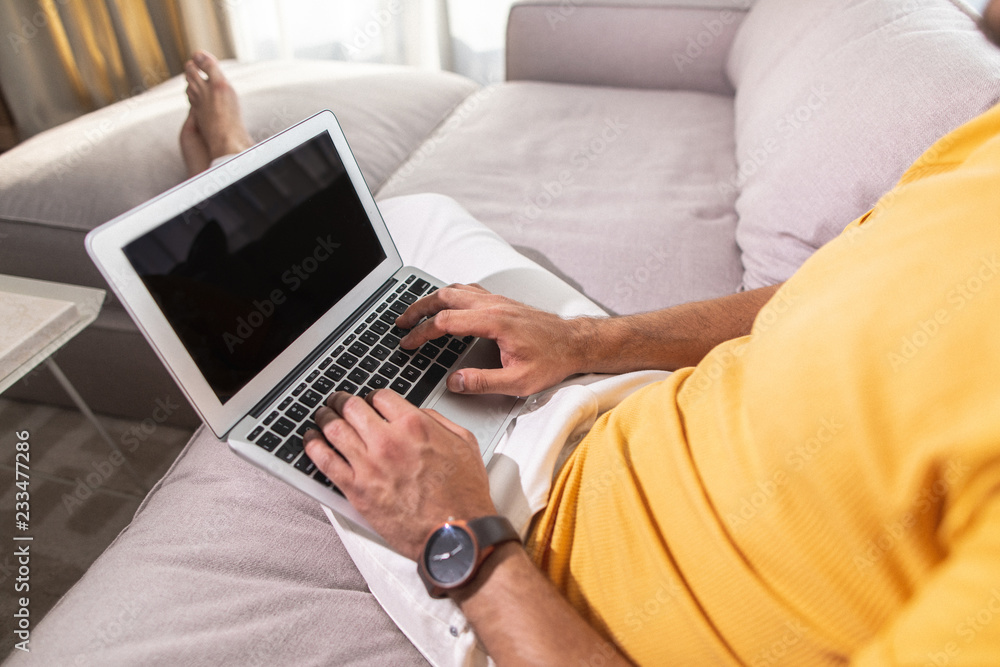 Adult male is siting on sofa and working with laptop Adult male is siting on sofa and working with laptop