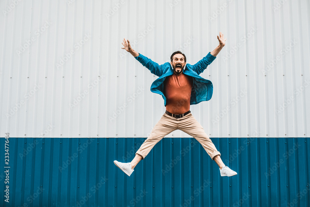 Too excited. Emotional young man in casual clothes jumping high while feeling happy and excited Too excited. Emotional young man in casual clothes jumping high while feeling happy and excited