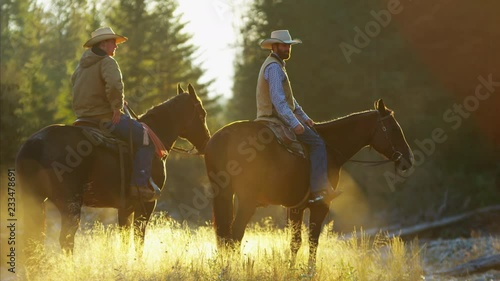 Cowboys Riding horses in the river wilderness area Canada