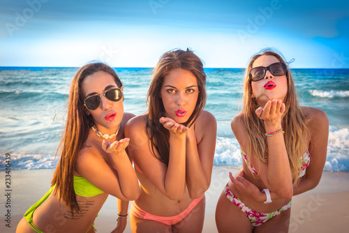 tres chicas muy sexys en bikini en la playa lanzando besos un día de verano © ismel leal
