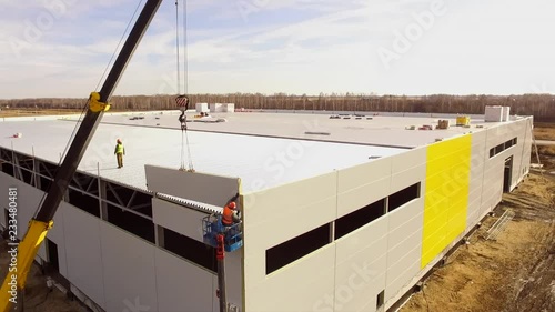 Aerial shot of object by the construction site buildings outdoors. camera moves and show an unfinished building, furnish. Aerial video footage of building place and installation of sandwich panels photo