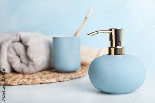 Stylish soap dispenser, holder with toothbrush and towel on table. Space for text