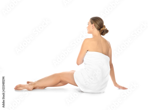 Young woman with soft towel sitting on white background