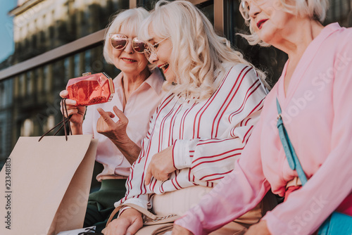 Fotografija Waist up portrait of three older ladies sitting near shopping center and talking
