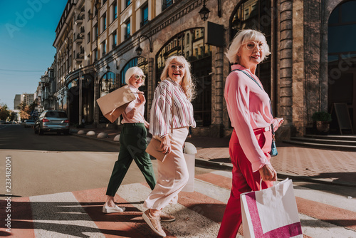 Three stylish adult women smiling and walking around town while holding ashopping bags photo