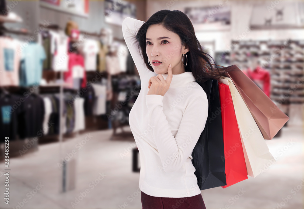 woman thinking and holding shopping bag at mall