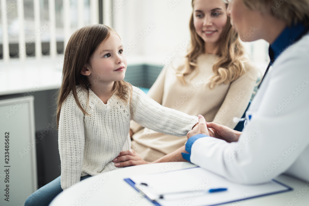 Concept of professional consultation in therapist practice. Waist up portrait of pediatrician woman measuring pulse of smiling girl in medical office Concept of professional consultation in therapist practice. Waist up portrait of pediatrician woman measuring pulse of smiling girl in medical office