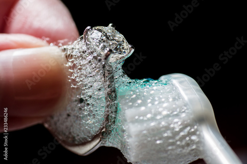 Woman's Hands Cleaning Diamond Ring With Toothbrush and Soap