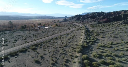 Aerial drone scene of truck traveling over road at river valley between eroded sandy hills. Sunset time. Calingasta, San Juan, Argentina. photo