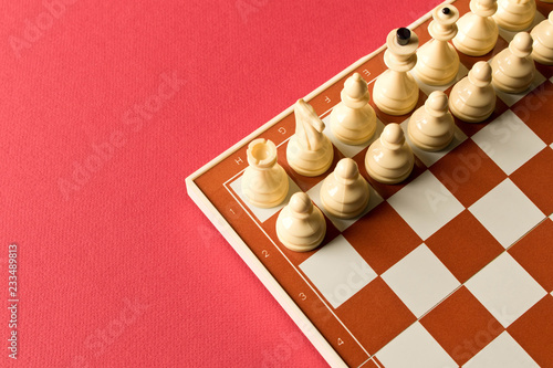 Board with white chess on red background.  The concept of the game of chess