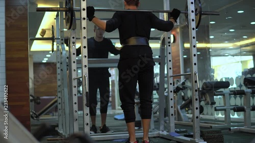 Young man performing Leg Barbell squat photo