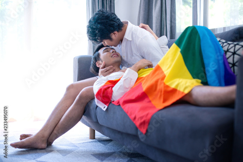 Sweet and cute shot of gay couple relaxing on sofa with rainbow flag, love and relationships concept