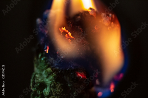 A marijuana bud consumed in flame, isolated macro close up.