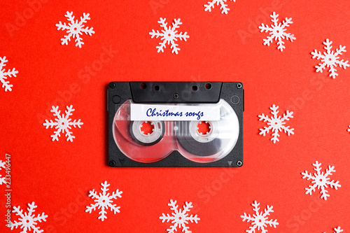 Audio cassette tape with decorative snowflakes on a red background. Music for Christmas mood.