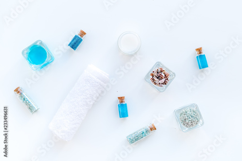 Sea salt for spa and aroma spa cosmetics near towel and shells on white background top view