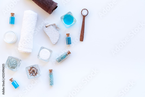 Sea salt for spa and aroma spa cosmetics near towel and shells on white background top view copy space