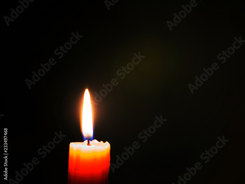 A candle is lit flame in complete darkness.