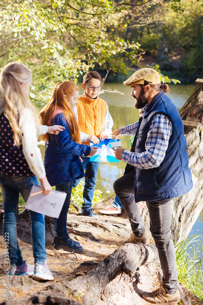 © zinkevych - Forest tour. Nice smart children standing in front of their guide while listening to him