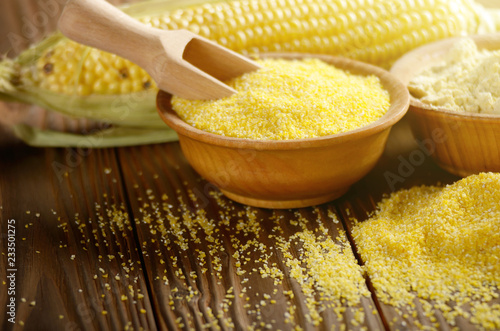 Bowl of corn grits corncob and corn flour on kitchen table photo