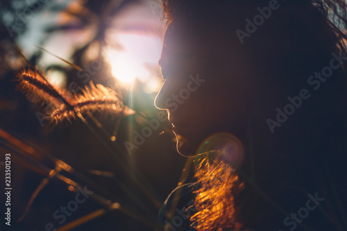 beautiful young woman on a field at sunset