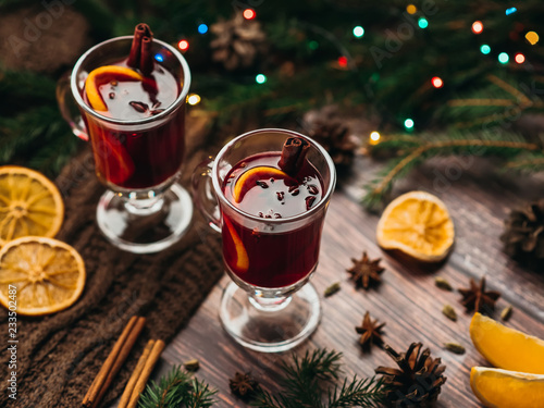two glasses with mulled wine on the table with orange slices and spices with winter Christmas decor