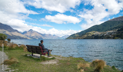 Man sitting on the chair near the waterfront of lake Wakatipu in Queenstown, New Zealand.