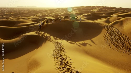 Aerial drone of Middle Eastern male camel owners in desert convoy photo