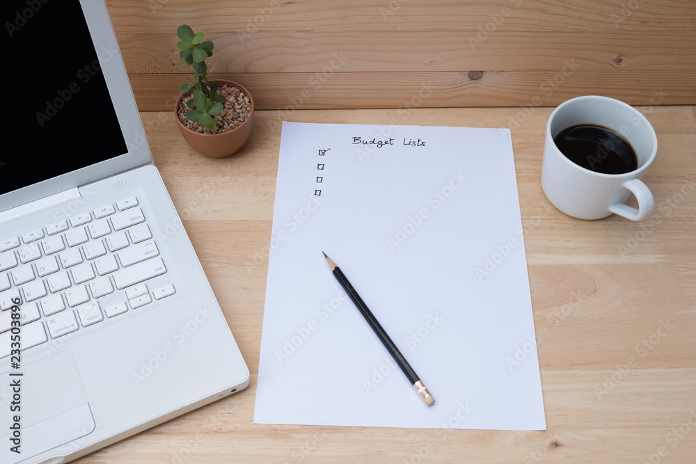 Paper check list for budget, laptop, coffee on wooden table. Paper check list for budget, laptop, coffee on wooden table.