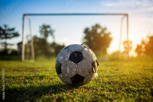 A ball on the green grass field for soccer football game under the sunset ray light. © nateejindakum