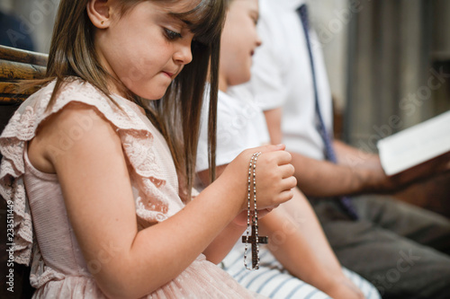 Little catholic girl praying with a rosary in her hands