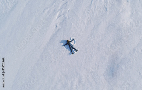 Wallpaper Mural Woman makes snow angel laying in the snow. Top view. Aerial foto. Torontodigital.ca