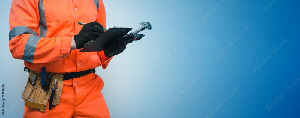 The measurer worker writes dimensions to his notebook. Building contract signing. Builder with construction project plans in the hands isolated on blue background. The measurer worker writes dimensions to his notebook. Building contract signing. Builder with construction project plans in the hands isolated on blue background.