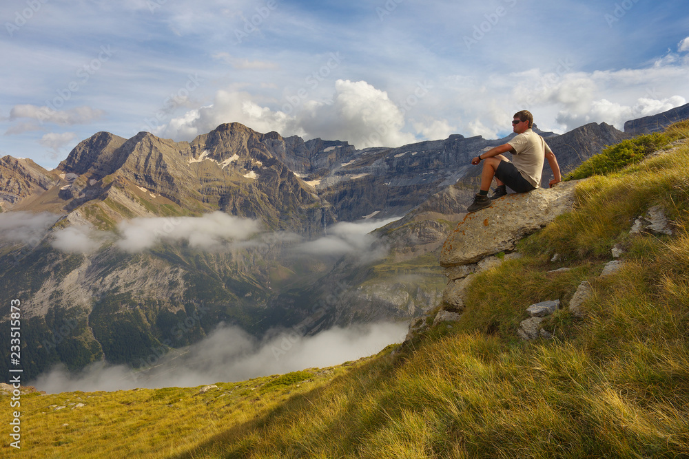 Resting tourist sitting on the stone with mountains on backround, Pyrenees Resting tourist sitting on the stone with mountains on backround, Pyrenees