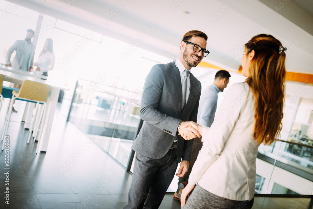 Young businessman and woman shake hands as hello in office portrait Young businessman and woman shake hands as hello in office portrait