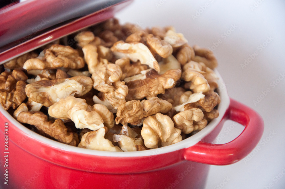 Obraz premium peeled walnuts in a small red saucepan