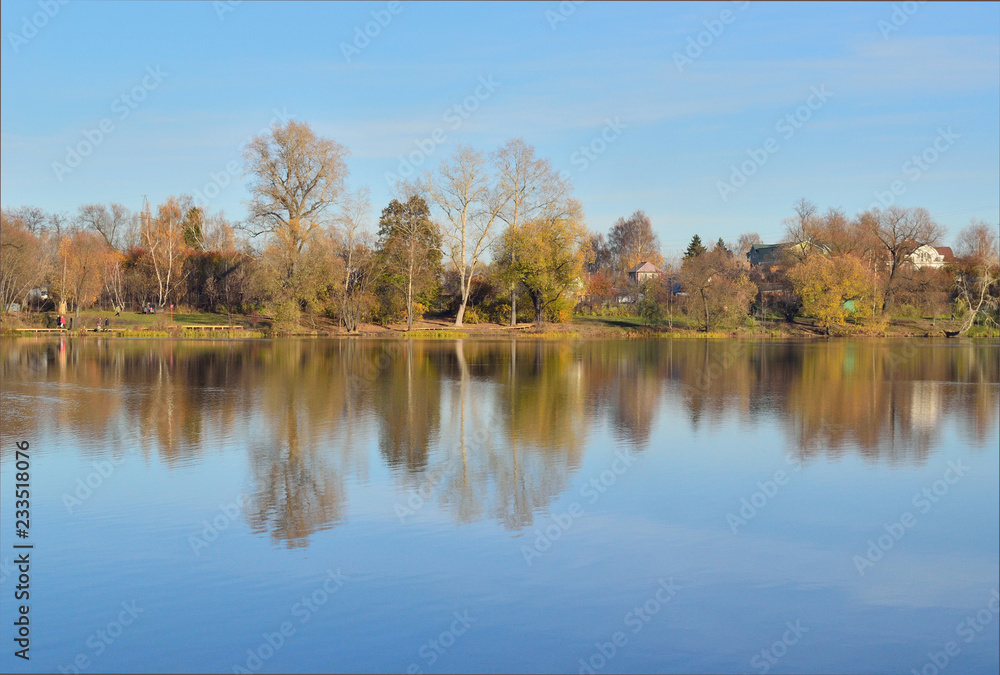 autumn landscape with a lake shore where yellow trees are reflected