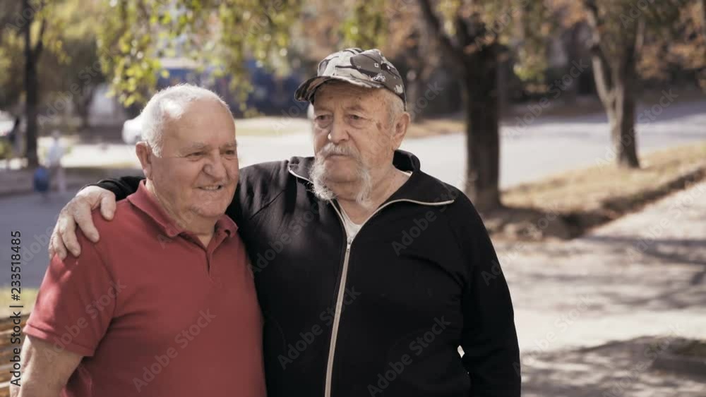 Portrait of aged lonely, but happy men friendly embracing at camera on street Portrait of aged lonely, but happy men friendly embracing at camera on street