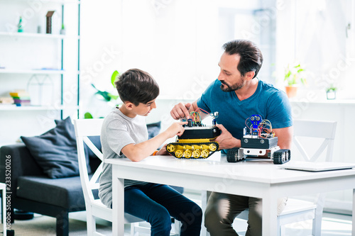 Photography Involved man and his little son constructing robotic devices