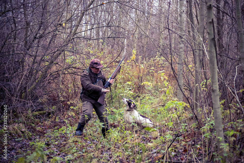male hunter, in the forest, with arms, dog Springer Spaniel, hunting, autumn