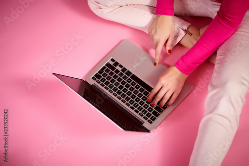 female hands on a laptop keyboard, businesswoman, on a light pink background