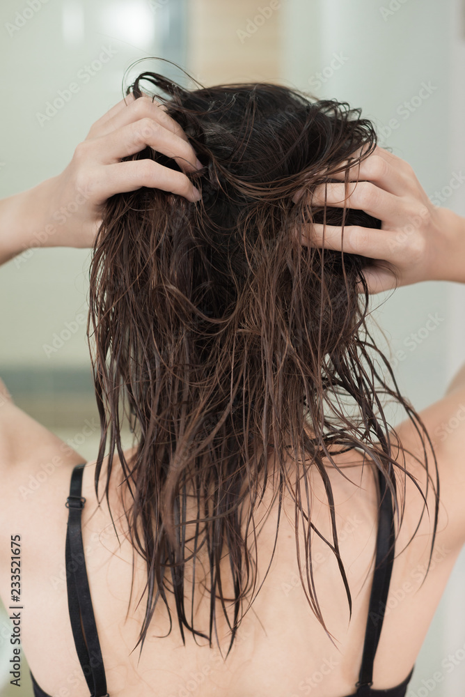 Naklejka premium Rear view of a young asian woman with wet hair after showering.