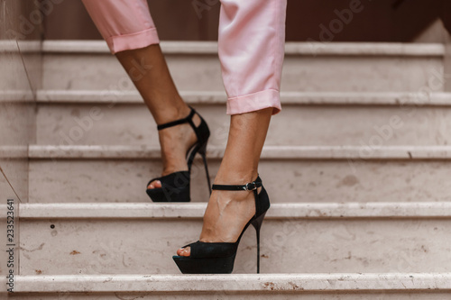Women's legs in black sandals. And pink pants