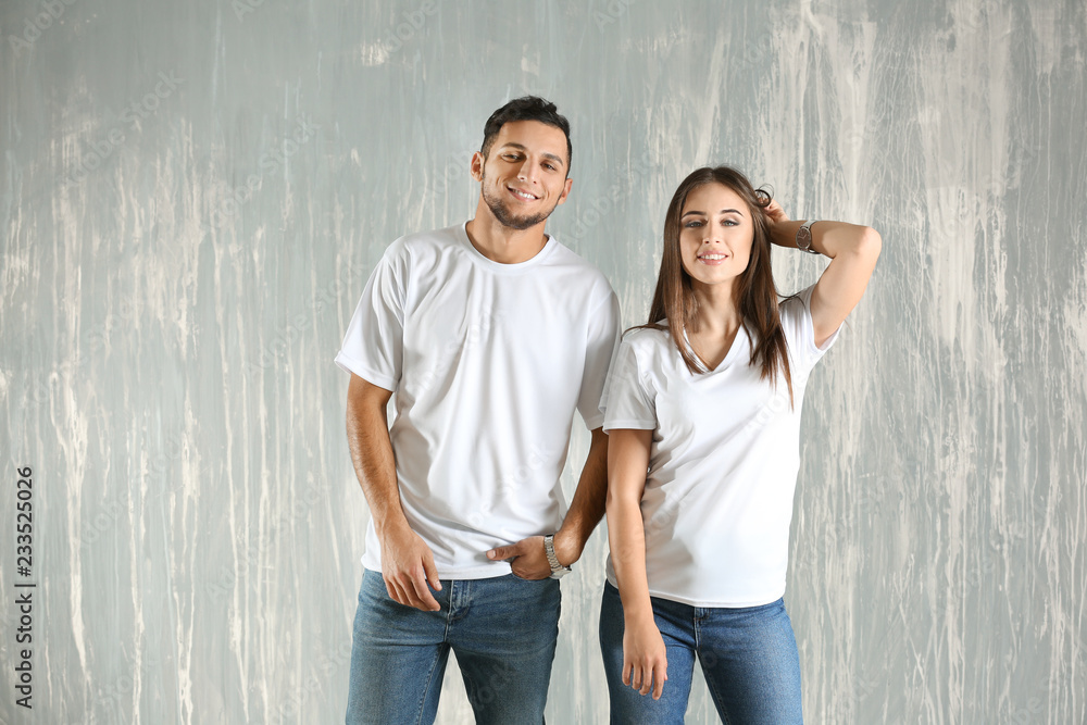 Young man and woman in stylish t-shirts on grey background