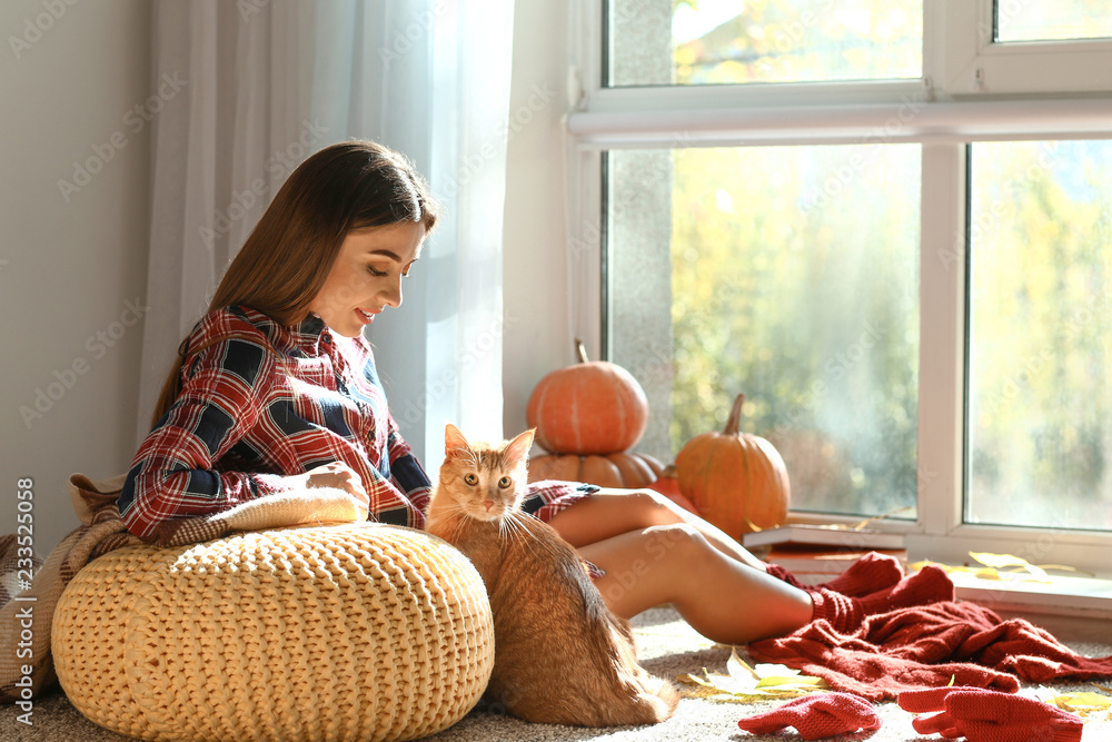 Woman with cute cat resting at home on autumn day - obrazy, fototapety, plakaty 