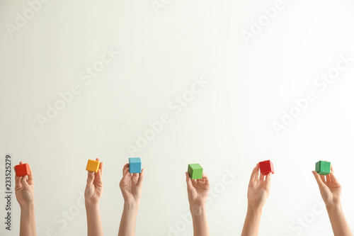Female hands holding color cubes on light background